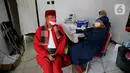 Petugas kepolisian berpakaian pejuang jaman berbincang dengan petugas medis saat vaksinasi Covid-19 di Polsek Pasar Rebo, Jakarta, Selasa (17/8/2021). Para petugas berkostum pejuang jaman dulu memeriahkan HUT ke-76 Republik Indonesia. (Liputan6.com/Angga Yuniar)