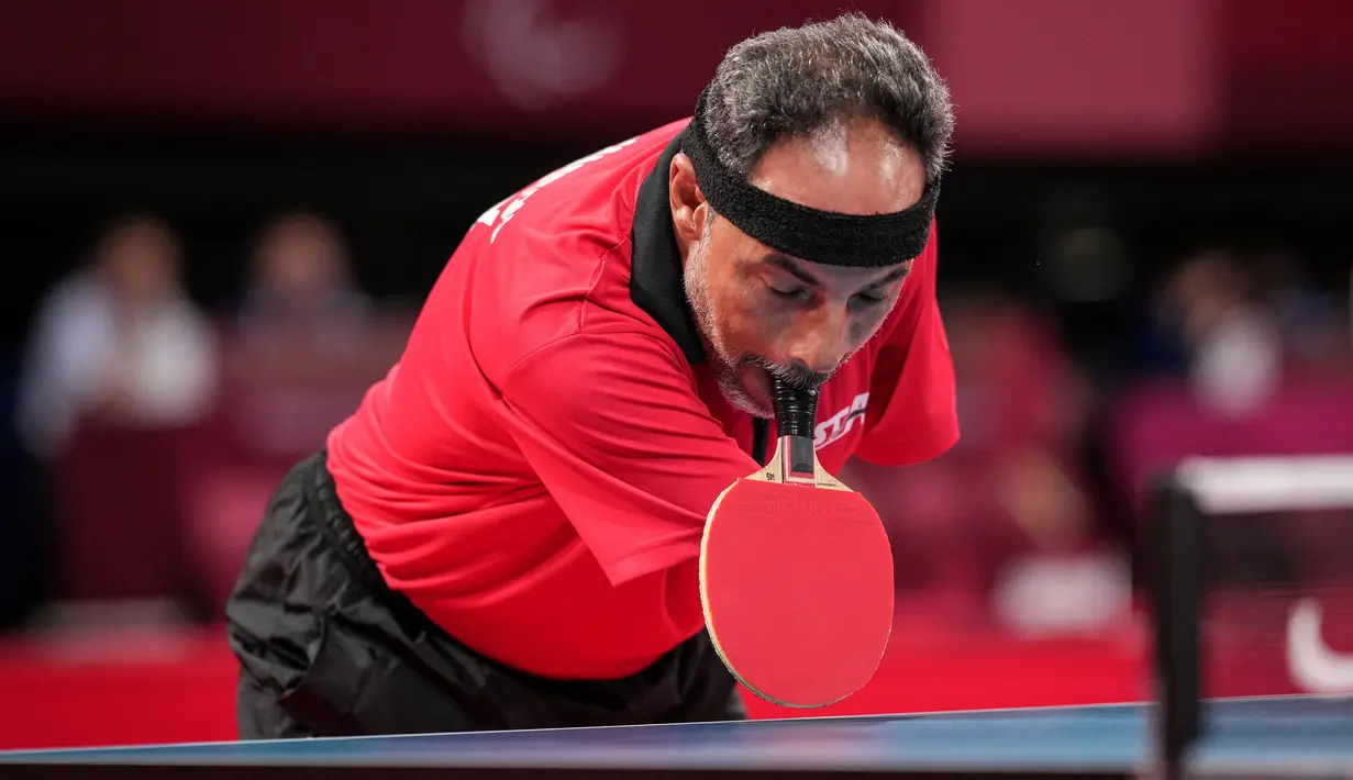 Petenis Mesir Ibrahim Elhusseiny Hamadtou mengambil raketnya dari meja sebelum laga Group E kelas 6 Tenis Meja Putra Paralimpiade Tokyo 2020 melawan Chao Chen dari China di Tokyo Metropolitan Gymnasium, Jumat (27/8/2021). (Yasuyoshi CHIBA / AFP)