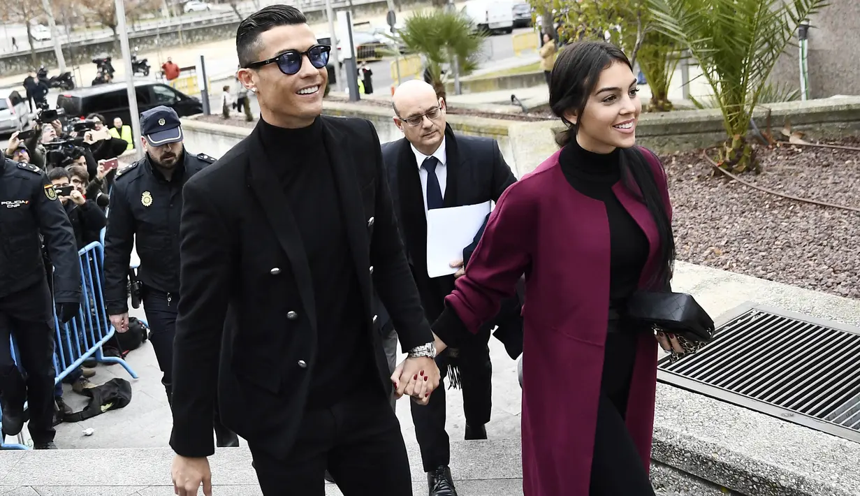Cristiano Ronaldo bersama kekasihnya, Georgina Rodriguez, tiba di kantor pengadilan untuk menghadiri sidang penggelapan pajak di Madrid, Spanyol (22/2/2019). (AFP/Oscar Del Pozo)