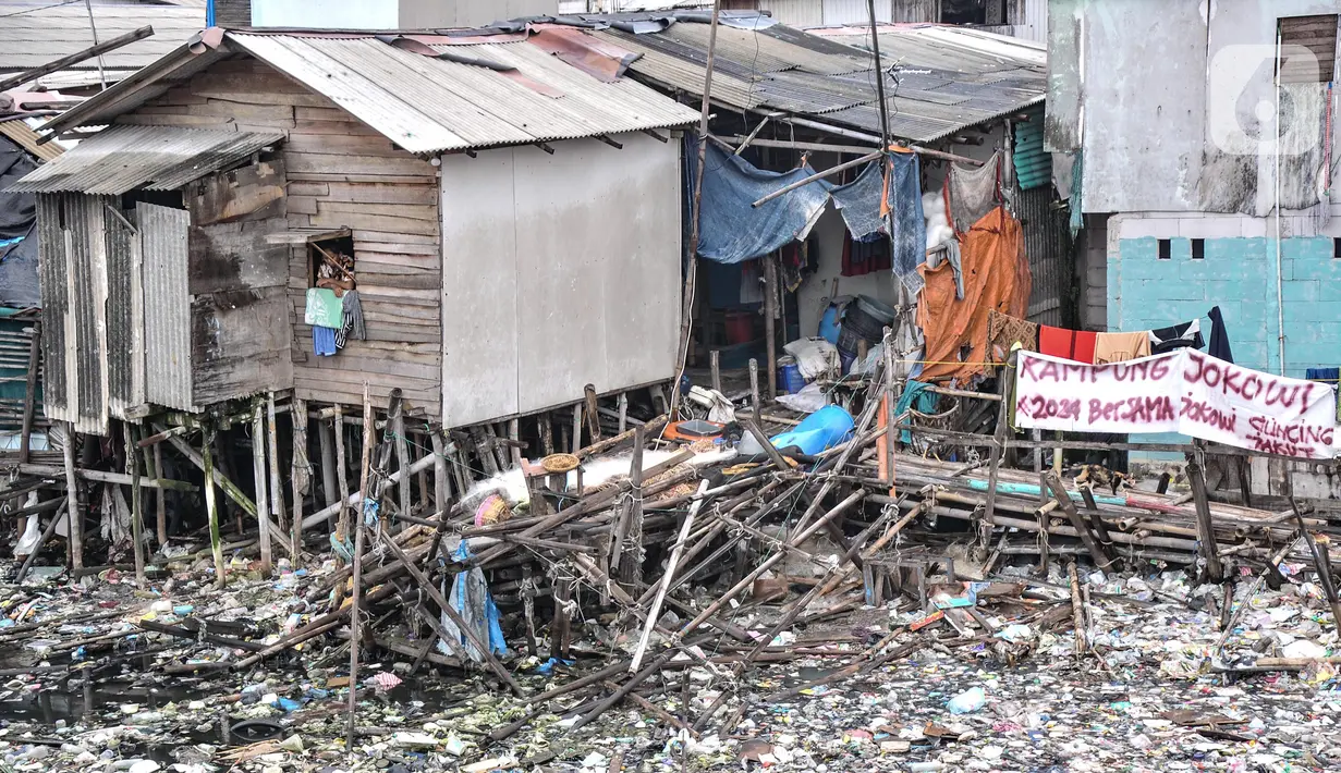 Seorang warga melihat ke luar jendela dengan lautan sampah mengelilingi di kawasan Kali Baru, Cilincing, Jakarta Utara, Rabu (23/2/2022). Mulai hari ini, lautan sampah tersebut dibersihkan oleh petugas terkait setelah ramai diberitakan. (merdeka.com/Iqbal S. Nugroho)