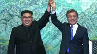 Pemimpin Korea Utara Kim Jong Un (kiri), dan Presiden Korea Selatan Moon Jae In berpegangan tangan dalam Konferensi Tingkat Tinggi (KTT) Antar-Korea di Panmunjom. (AFP/Arsip)