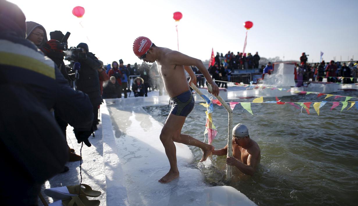 Para peserta keluar dari kolam renang yang terbuat dari sungai Songhua yang membeku pada Kompetisi Renang Es Harbin di Provinsi Heilongjiang, Senin (5/1/2016). (REUTERS/Aly Song)