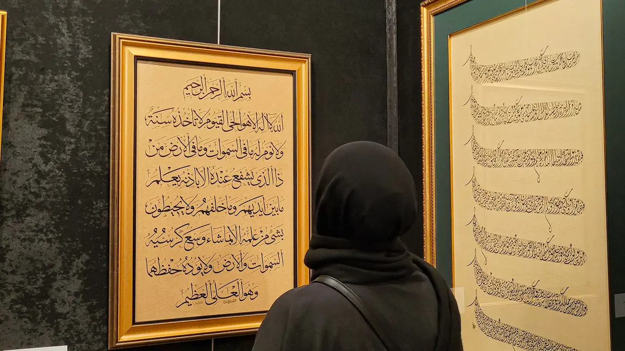 Wallpaper kaligrafi indah berupa muslim sedang membaca ayat suci Al-Qur'an di dinding