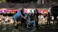 Pengunjung mengenakan kursi roda menghindar saat terjadi penembakan di Las Vegas, Nevada (1/10). Pelaku penembakan disebut menembak seorang petugas keamanan dan polisi setempat. (David Becker/Getty Images/AFP)