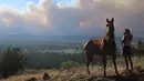<p>Janetta Kathleen dan kudanya, Squish, menyaksikan asap mengepul di pinggiran Flagstaff, Arizona, Minggu (12/6/2022). Evakuasi telah diperintahkan untuk rumah-rumah di daerah tersebut. Pihak berwenang mengatakan petugas pemadam kebakaran menanggapi kebakaran hutan sekitar enam mil di utara Flagstaff yang telah memaksa evakuasi. (AP Photo/Felicia Fonseca)</p>