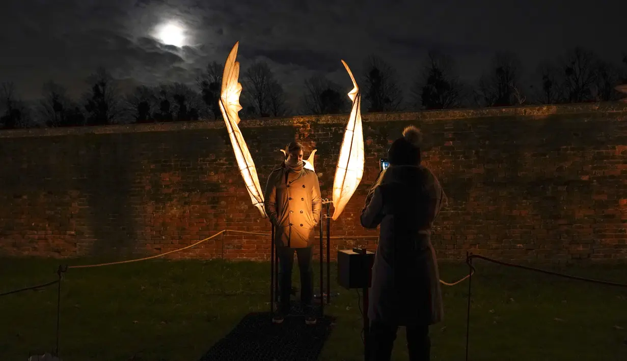 Orang-orang berfoto di samping instalasi Palace of Light, di Hampton Court Palace, London, Rabu (7/12/2022). Kings Beast adalah patung heraldik yang di pesan sendiri oleh Raja Henry VII.( Foto AP/Alberto Pezzali)