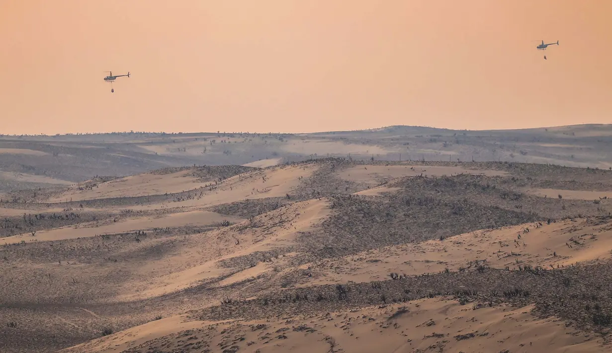 Dua helikopter kembali dari menyiramkan air ke titik-titik api dari Kebakaran Smokehouse Creek, Rabu, 28 Februari 2024, di Canadian, Texas. (AP Photo/David Erickson)