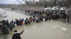 Ribuan migran menyeberangi sungai dengan berpegangan pada seutas tali di perbatasan Yunani-Makedonia, Idomeni, Yunani (14/3/2016). Lebih dari 1.000 migran nekat menembus sungai untuk mencari jalan keluar perbatasan. (Reuters/Stoyan Nenov)
