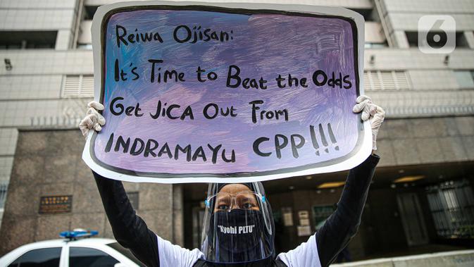 Seorang warga dari Indramayu membawa poster saat menggelar aksi di depan Kedubes Jepang, Jakarta, Rabu (21/10/2020). Dalam aksinya, mereka menolak pembangunan PLTU 2 di Indramayu karena akan menyebabkan pencemaran udara dan rusaknya lahan pertanian. (Liputan6.com/Faizal Fanani)