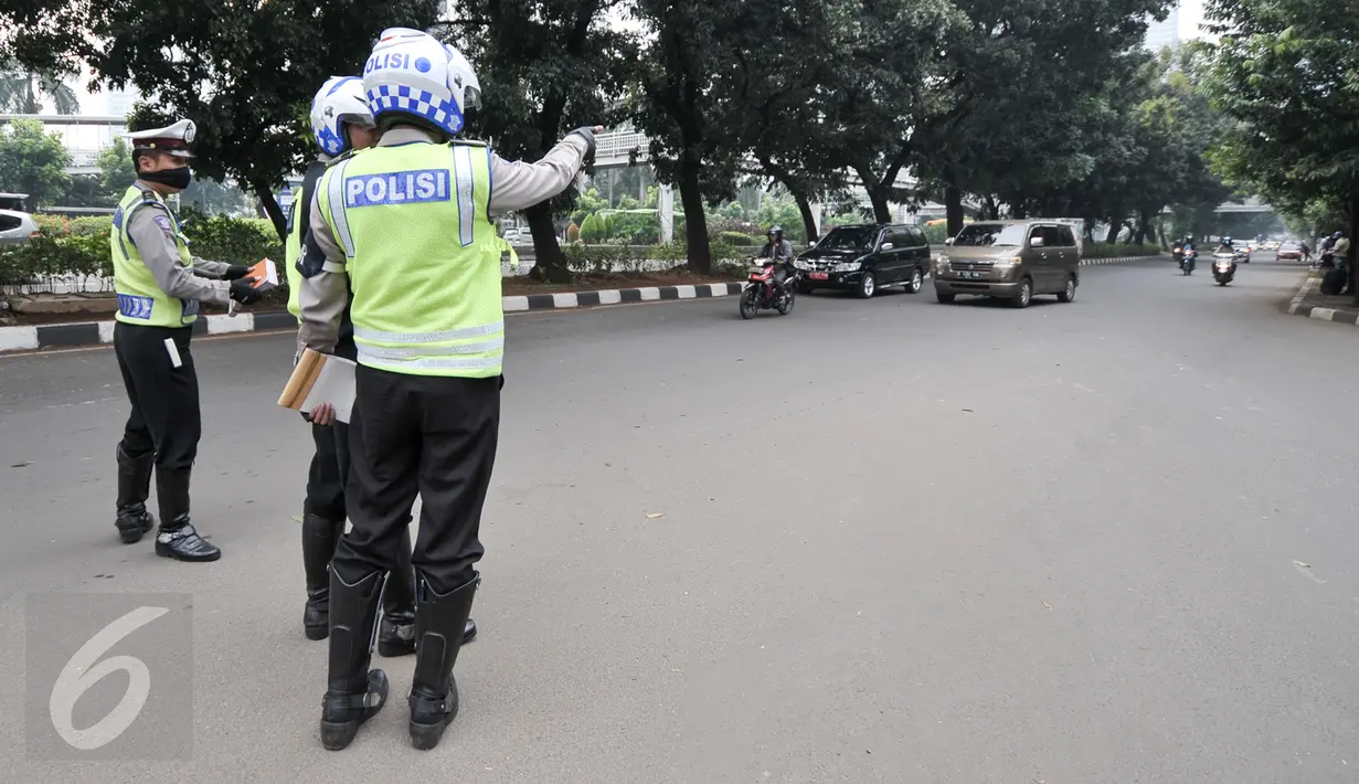 Sejumlah petugas mengawasi kendaraan yang melintas di kawasan Sudirman, Jakarta, Selasa (30/8). Pembatasan kendaraan bermotor berdasarkan pelat nomor ganjil dan genap di sejumlah jalan protokol di Jakarta resmi diberlakukan. (Liputan6.com/Yoppy Renato)