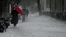Orang-orang berjalan melintas di jalan saat salju turun di Beijing, China, Minggu (7/11/2021). Badai salju awal musim telah menyelimuti sebagian besar Cina utara termasuk ibu kota Beijing, mendorong penutupan jalan dan pembatalan penerbangan. (Noel Celis / AFP)