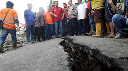 Gubernur DKI Anies Baswesdan meninjau lokasi jalan retak di  Kelurahan Kebon Manggis, Kecamatan Matraman, Jakarta Timur, Jumat (16/2). Kehadiran Anies yang mengenakan baju tradisional China itu mengundang perhatian warga sekitar (Liputan6.com/Johan Tallo)