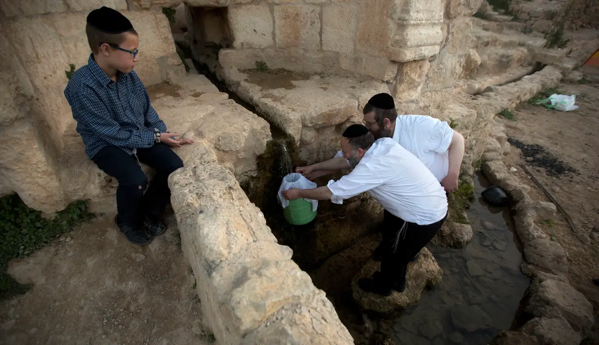 Penganut Yahudi ultra-Ortodoks mengambil air dari mata air untuk membuat matza di dekat Yerusalem (4/4). Bagi bangsa Israel, perayaan paskah ini adalah hari peringatan akan terlepasnya mereka dari perbudakan bangsa Mesir. (AP Photo/Sebastian Scheiner)
