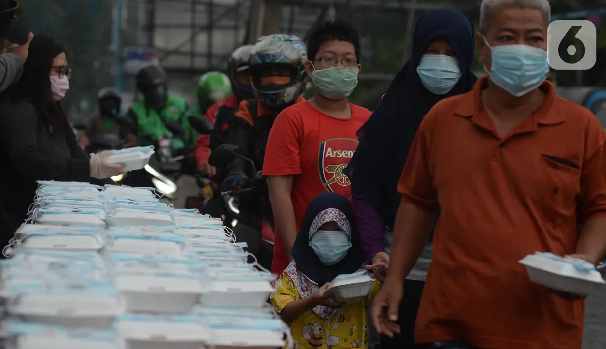 Warga menerima pembagian nasi bungkus gratis di Posko Perjuangan Rakyat (POSPERA), Jakarta, Rabu (10/3/2021). Pembagian 500 nasi bungkus beserta masker dan vitamin secara gratis setiap harinya dalam bentuk meringankan beban warga di tengah pandemi Covid-19. (merdeka.com/Imam Buhori)