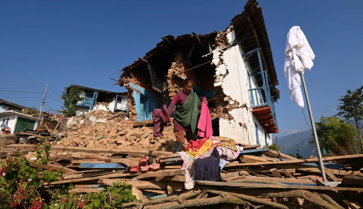 <p>Seorang korban selamat mencari barang-barang di antara reruntuhan rumahnya yang rusak di Khalanga, distrik Jajarkot, pada tanggal 6 November 2023. (PRAKASH MATHEMA/AFP)</p>