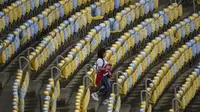 Pendukung Peru melewati kursi kosong Stadion Maracana jelang laga melawan Bolivia pada Copa America 2019, Senin (18/6/2018). (AFP/Mauro Pimentel)