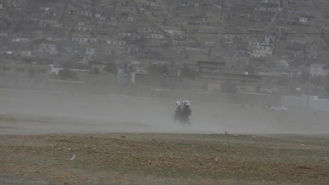 Siswi Afghanistan berjalan saat badai pasir di pinggiran Kabul, Afghanistan (25/8/2020). Sebuah badai pasir hebat melanda Kabul. Badai menyebabkan jarak pandang jadi berkurang. (AP Photo / Rahmat Gul)