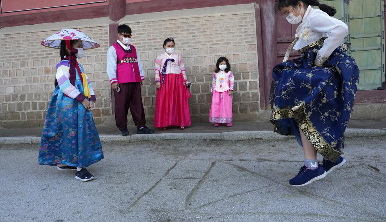 Seorang gadis mengenakan masker sebagai tindakan pencegahan terhadap virus corona bermain saat dia mengunjungi anggota keluarganya untuk merayakan liburan Chuseok, Hari Thanksgiving versi Korea, di Istana Gyeongbok di Seoul, Korea Selatan, Rabu (22/9/2021). ( AP Photo/Ahn Young-joon)