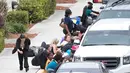 Para penumpang berlindung di samping kendaraan saat terjadi penembakan di Bandara Fort Lauderdale, Florida, AS (6/1). Ratusan orang dilaporkan berada di sekitar lokasi saat penembakan terjadi. (AP Photo/Wilfredo Lee)