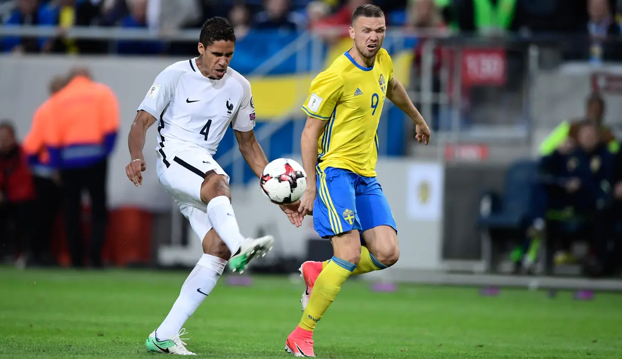 Bek Prancis, Raphael Varane berusaha menendang bola dari kejaran Penyerang Marcus Berg saat bertanding pada kualifikasi Piala Dunia 2018 di Friends Arena, Solna, Stockholm (9/6). Swedia menang atas Prancis dengan skor 2-1. (Marcus Eriksson/TT via AP)