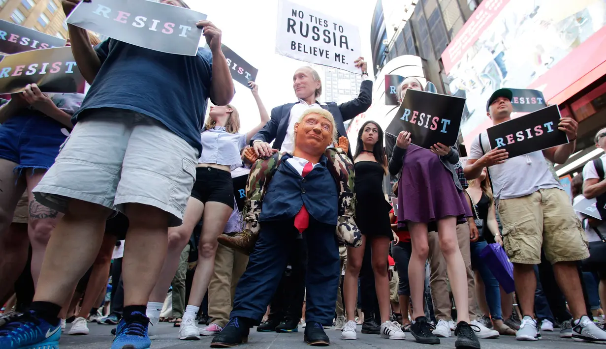Seorang pendemo (tengah) membawa boneka berwajah Presiden AS, Donald Trump dalam demontrasi di Times Square, New York, Rabu (26/7). Demonstrasi digelar setelah Trump melarang kaum transgender menjadi personel militer AS. (AP/Frank Franklin II)
