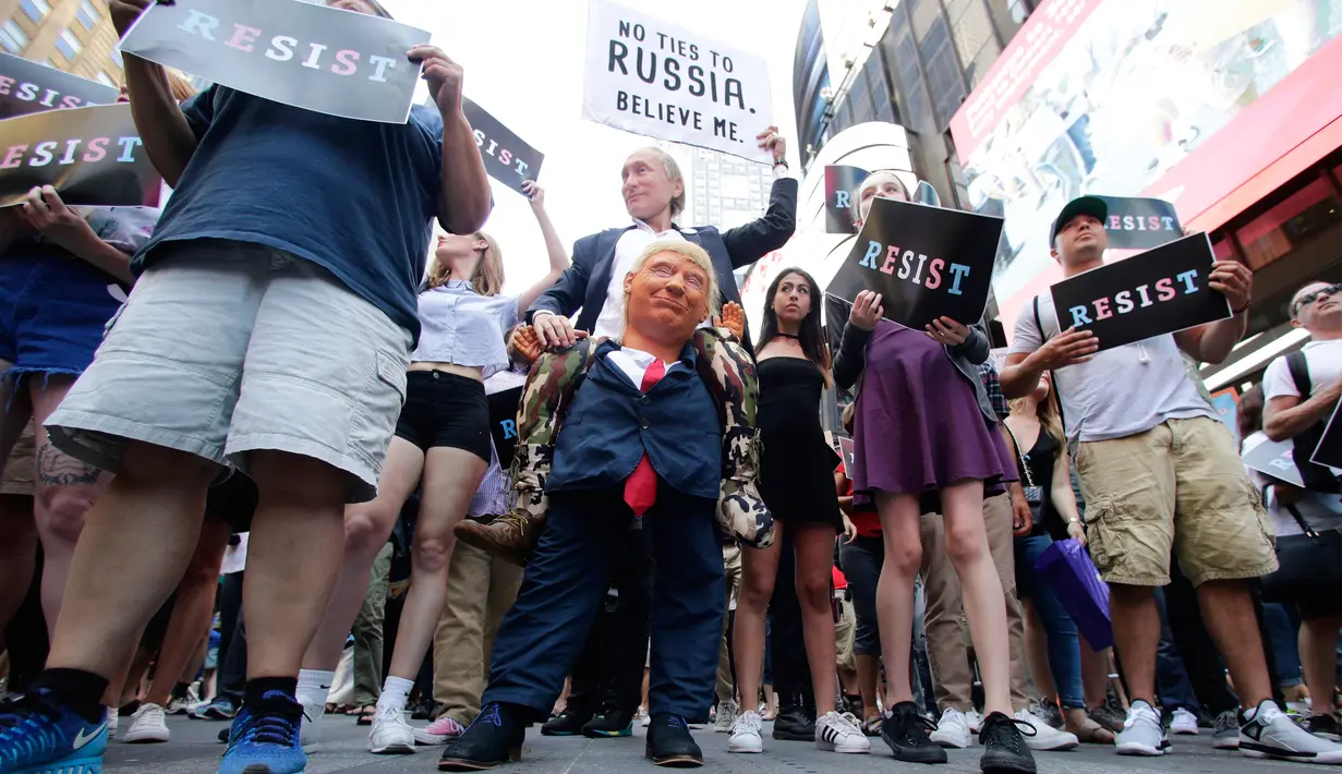 Seorang pendemo (tengah) membawa boneka berwajah Presiden AS, Donald Trump dalam demontrasi di Times Square, New York, Rabu (26/7). Demonstrasi digelar setelah Trump melarang kaum transgender menjadi personel militer AS. (AP/Frank Franklin II)