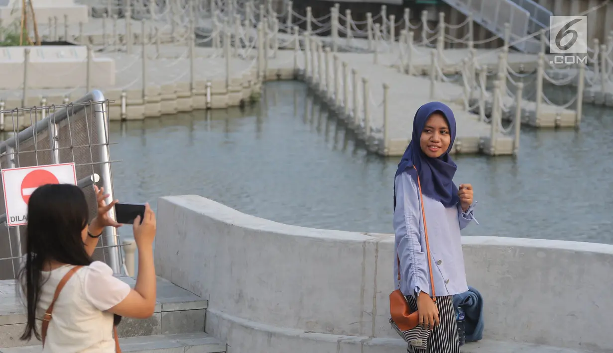 Warga berfoto-foto di kawasan pedestrian Kali Besar, Kota Tua, Jakarta, Rabu (11/7). Proyek revitalisasi Kali Besar itu telah diresmikan dan dibuka untuk umum oleh Wakil Gubernur Sandiaga Uno akhir pekan lalu. (Liputan6.com/Arya Manggala)