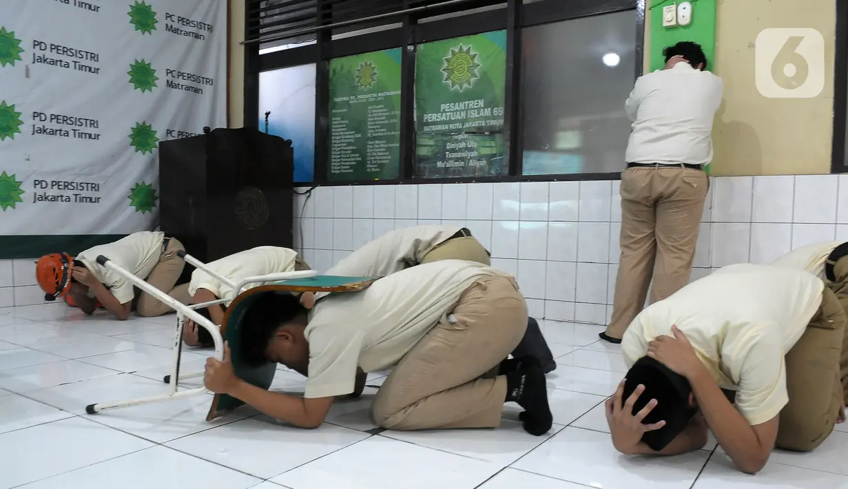 Sejumlah santri melindungi kepada mereka dengan tangan, helm, dan kursi saat pelatihan tanggap bencana dan kebakaran yang dilakukan oleh Badan Penanggulangan Bencana Daerah (BPBD) DKI Jakarta bersama Pemadam Kebakaran DKI Jakarta di Madrasah Aliyah Swasta Persatuan Islam (MAS Persis) 69, Matraman, Jakarta, Selasa (19/9/2023). (merdeka.com/Imam Buhori)
