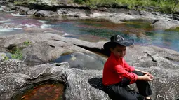 Seorang anak saat duduk santai di bebatuan Sungai Cano Cristales atau disebut "sungai lima warna" terlihat di Taman Nasional Sierra de La Macarena, provinsi Meta, Kolombia (27/9). (AFP PHOTO/John Vizcaino)