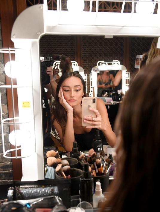 Model berselfie di belakang panggung sebelum tampil mengenakan The Australian Collection Show 2019 selama Miami Swim Week di Miami Beach, Florida (14/7/2019). Miami Swim Week menampilkan pakaian renang yang berlangsung 11 - 16 Juli 2019. (AFP Photo/Jason Koerner)