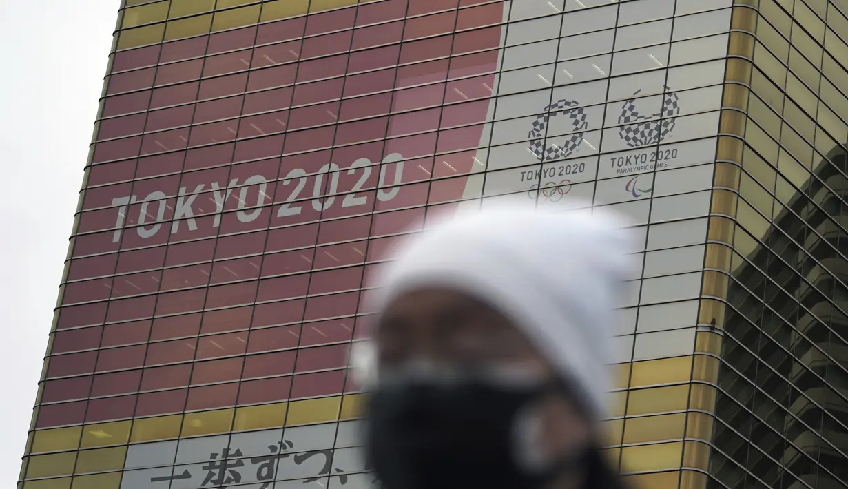 Seorang pria yang mengenakan masker berjalan di dekat spanduk Olimpiade dan Paralimpiade Tokyo 2020, di Tokyo, Jepang pada 27 Januari 2021. Olimpiade 2020 Tokyo yang ditunda terkait pandemi virus corona Covid-19 dijadwalkan ulang untuk diadakan pada musim panas ini. (AP Photo/Eugene Hoshiko)
