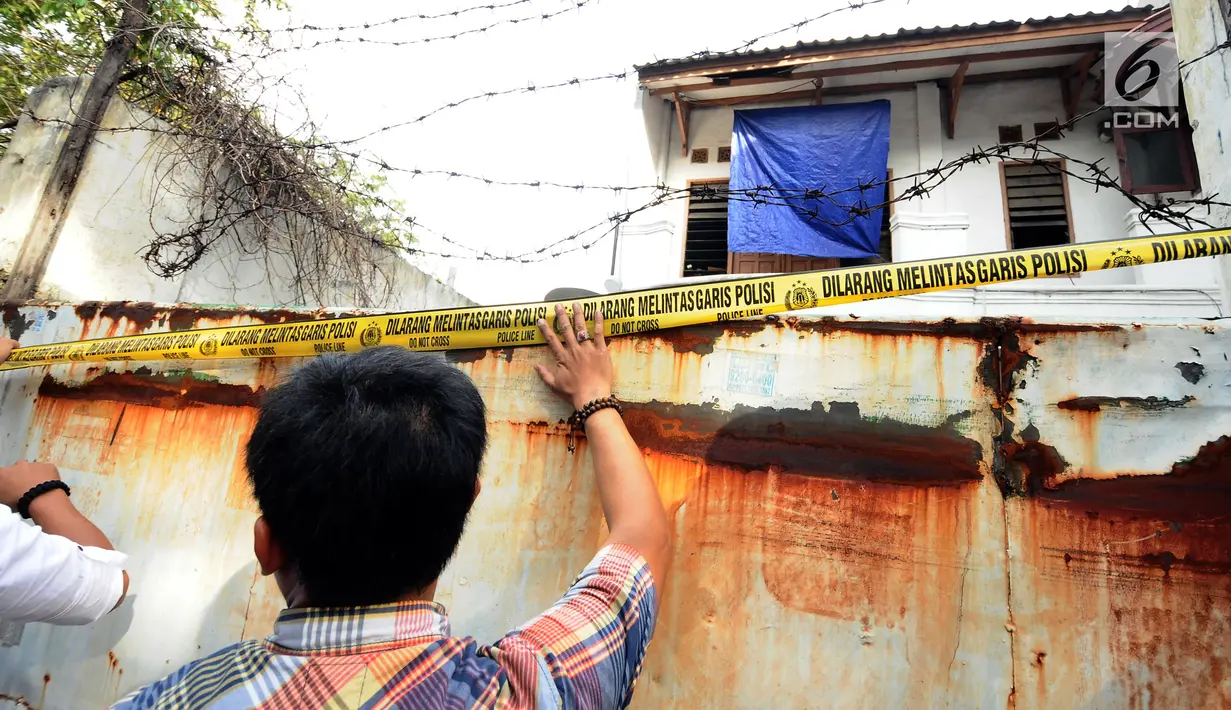  Petugas memasang garis polisi usai menggeledah rumah tersangka penampung TKI Ilegal di Jalan Percetakan Negara X, Jakarta, Rabu (31/5). Bersama satu tersangka, petugas Dirtipidum Mabes Polri mencari barang bukti baru. (Liputan6.com/Helmi Fithriansyah)