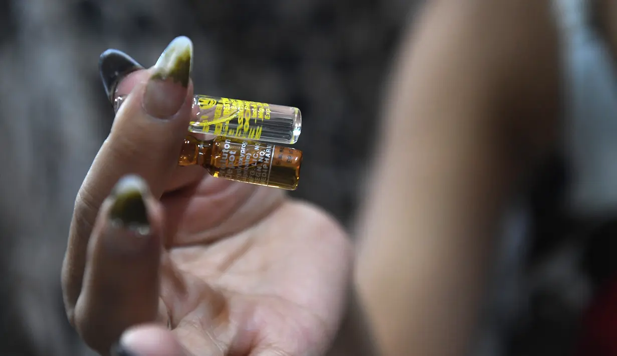 Jessica Nguyen (31) mempersiapkan dosis suntik hormon di tokonya, Ho Chi Minh, Vietnam (30/3). Vietnam merupakan salah satu negara yang menolak keras transgender. (AFP Photo/Hoang Dinh Nam)