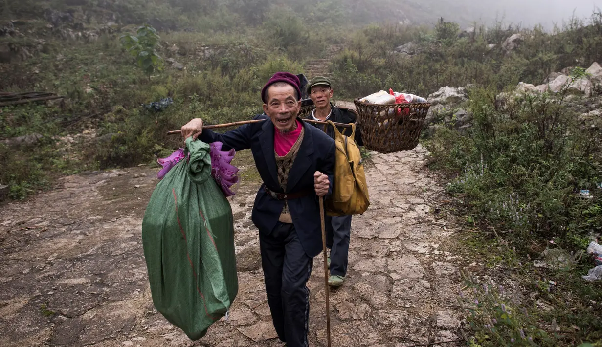 Dua pria berjalan menuju gua di Desa Zhongdong, Provinsi Guizhou, China (6/10/2016).  Menurut penduduk setempat gua tersebut juga dinilai sangat nyaman dan aman ketika cuaca buruk melanda. (AFP Photo / FredDufour)