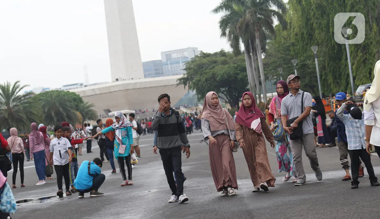 Warga berjalan-jalan di kawasan Monumen Nasional, Jakarta, Rabu (25/12/2019). Libur perayaan Natal 2019 dimanfaatkan warga Jakarta dan sekitarnya berwisata di Monumen Nasional. (Liputan6.com/Helmi Fithriansyah)