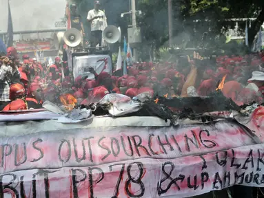 Buruh membakar keranda mayat sebagai simbol kekecewaan terhadap kebijakan pemerintah di Jalan Medan Merdeka Barat, Jakarta, Senin (1/5). (Liputan6.com/Yoppy Renato)