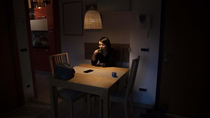 Elisabetta Teti, spesialis penyakit menular berusia 39 tahun, meminum kopinya saat sarapan di ruang tamunya, di Roma, 7 November 2020. Hari kerja dimulai dalam kegelapan, suaminya masih tertidur ketika dia menyelinap keluar dari apartemen mereka ke Rumah Sakit. (AP Photo/Alessandra Tarantino)