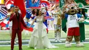 Penyanyi Inggris, Robbie Williams dan penyanyi soprano Rusia Aida Garifullina berduet pada upacara pembukaan Piala Dunia 2018 di Stadion Luzhniki, Kamis (14/6). Tak tertinggal maskot Piala Dunia 2018 Zabivaka berada di antara keduanya. (AP/Matthias Schrad