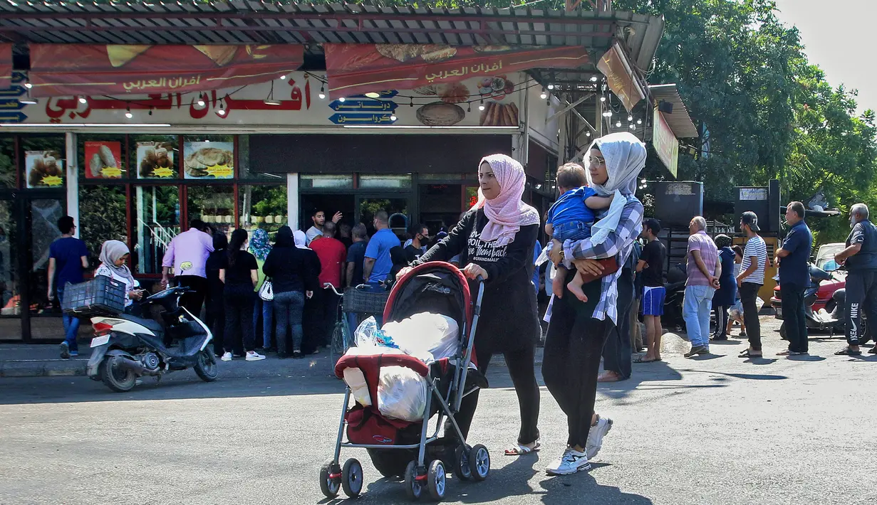 Warga Lebanon antre roti di depan toko roti di kota pesisir selatan Sidon, Jumat (13/8/2021). Tanpa masker, warga Lebanon berbondong-bondong ke toko roti sebelum fajar untuk membeli roti yang terjangkau di tengah krisis ekonomi parah yang memicu berbagai kelangkaan bahan pokok. (Mahmoud ZAYYAT/AFP)