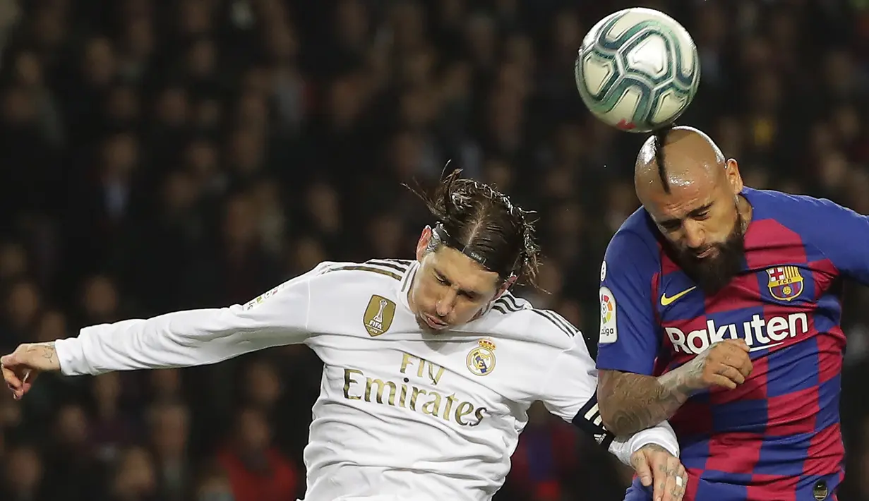 Bek Real Madrid, Sergio Ramos berebut bola udara dengan gelandang Barcelona,  Arturo Vidal pada pertandingan lanjutan La Liga Spanyol di stadion Camp Nou (18/12/2019). Barcelona bermain imbang 0-0 atas Real Madrid. (AP Photo/Emilio Morenatti)