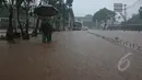 Seorang Pejalan kaki sedang berjalan melawati banjir yang berada di jalan Letjen Suprapto Cempaka Putih, Jakarta, Senin (9/2/2015). (Liputan6.com/Herman Zakharia)