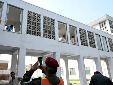 Para pekerja menyingkirkan pecahan kaca jendela setelah insiden kebakaran di luar bangsal Kesehatan Ibu dan Anak (MCH) di Rumah Sakit Pakistan Institute of Medical Sciences (PIMS), Islamabad, Pakistan, Rabu, 26 Agustus 2026. (AFP/  Aamir Qureshi)
