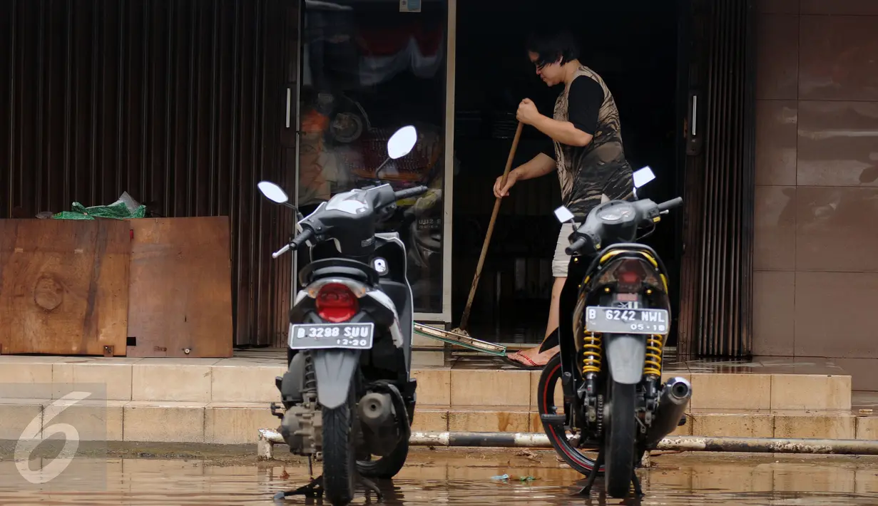 Pekerja membersihkan sisa banjir dari depan pertokoan di Jalan Kemang Raya, Minggu (28/8). Sejumlah kendaraan terendam air di kawasan Kemang Raya pasca hujan deras di Jakarta pada Sabtu (27/8). (Liputan6.com/Helmi Fithriansyah)