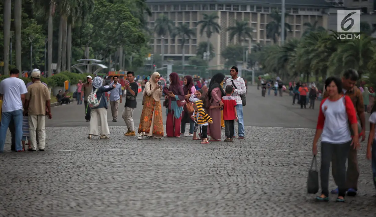 Sejumlah pengunjung berjalan-jalan di kawasan Monumen Nasional (Monas), Jakarta, Sabtu (22/12). Libur sekolah yang berbarengan dengan libur Natal dan Tahun Baru dimanfaatkan masyarakat untuk pergi berwisata ke Monas. (Liputan6.com/Faizal Fanani)