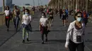 Warga barjalan di trotoar pinggir laut di Barcelona, Spanyol, Sabtu (2/5/2020). Pelonggaran lockdown memungkinkan warga Spanyol keluar rumah untuk kali pertama dalam tujuh pekan terakhir. (AP Photo/Emilio Morenatti)