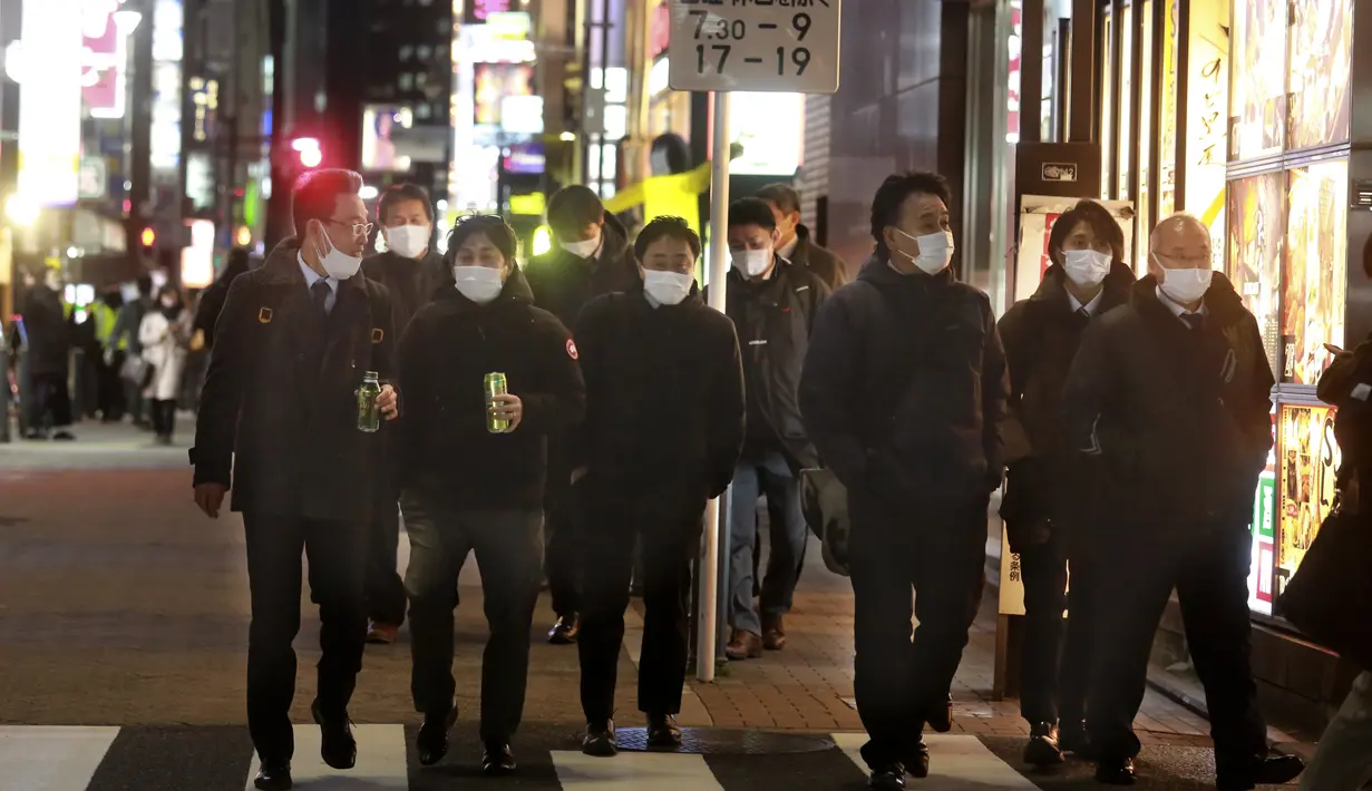 Orang-orang memakai masker untuk melindungi dari penyebaran virus corona berjalan di sepanjang jalan yang dipenuhi bar dan restoran di Tokyo, Rabu (19/1/2022). Para pemimpin lokal mempersingkat jam buka restoran, karena kasus omicron mencapai rekor tertinggi di ibu kota. (AP Photo/Koji Sasahara)