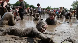Christian Kubanek, 4, bermain dalam kubangan lumpur saat Mud Day atau Hari Lumpur di Michigan, negara bagian AS, Selasa (9/7/2019). Para peserta perayaan yang menjadi tradisi setiap tahun ini merupakan anak-anak untuk agar mereka bersenang-senang selama liburan musim panas.  (AP/Carlos Osorio)