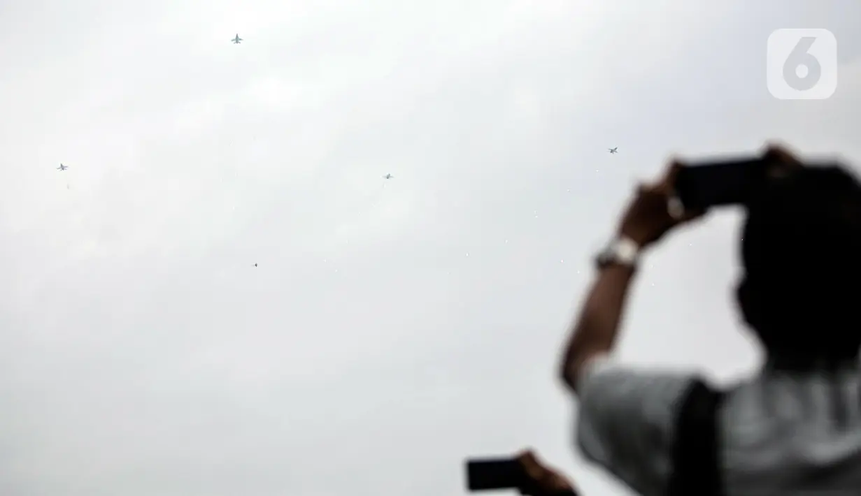 Penampilan atraksi pesawat tempur F-16 diambil gambarnya oleh warga saat perayaan HUT ke-77 TNI di Jakarta, Rabu (5/10/2022). Kegiatan yang diikuti oleh seluruh kesatuan jajaran TNI ini dalam rangka menyambut HUT ke-77 TNI. (Liputan6.com/Faizal Fanani)