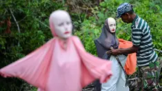 Seorang penduduk desa memasangkan manekin di tengah lahan perkebunannya di Lamteuba, provinsi Aceh pada 26 Agustus 2019. Penempatan maneken di tengah lahan perkebunan tersebut sebagai upaya mengurangi serangan hama babi dan monyet yang merusak tanaman. (CHAIDEER MAHYUDDIN / AFP)