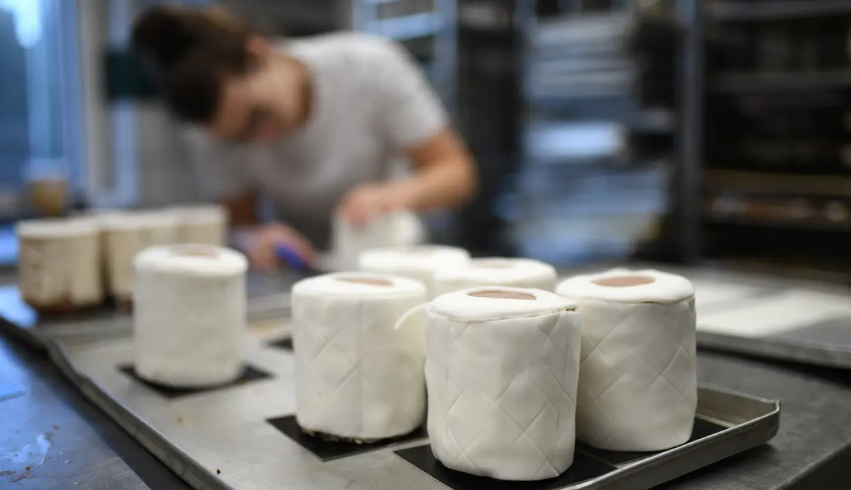 Andrea Schulz menyiapkan kue berbentuk tisu toilet di toko roti Schuerener Backparadies di Dortmund, Jerman, 26 Maret 2020. Kelangkaan kertas tisu toilet memunculkan ide bagi pemilik toko roti itu, Tim Kortuem, membuat kue menyerupai barang yang diburu warga di tengah Covid-19. (Ina FASSBENDER/AFP)